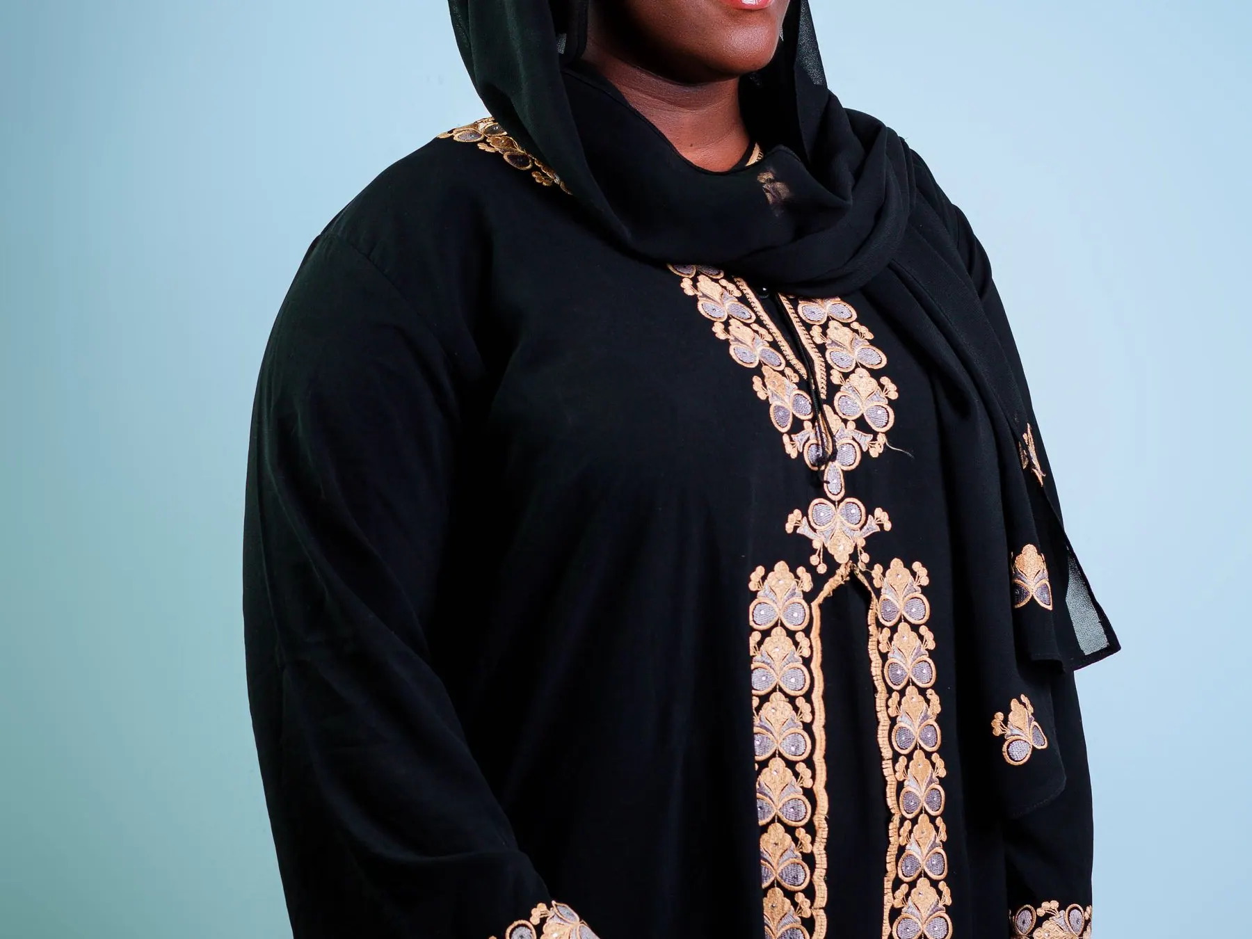 Woman wearing a black abaya with gold embroidery